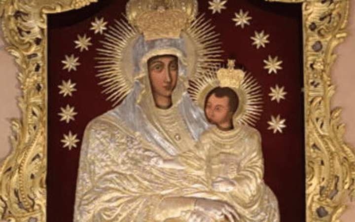 Our Lady of Šiluva — Šiluva. An icon of Mary holding the Child, covered in a silver riza, candles at the edge of the frame.